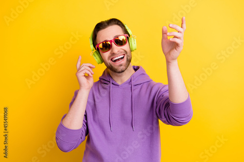 Photo of young man happy positive smile have fun dance listen headphones isolated over yellow color background