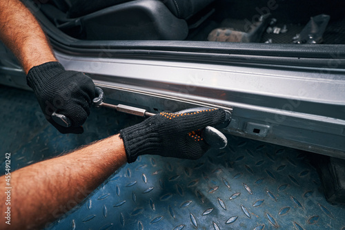 Person holding straightening tool pressed to car side door frame photo