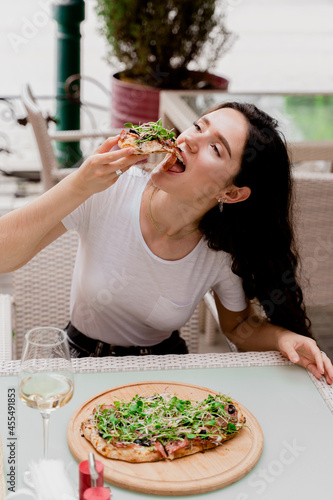 Girl with pinsa romana in cafe on summer terrace. Young woman eating pinsa and drinking wine photo