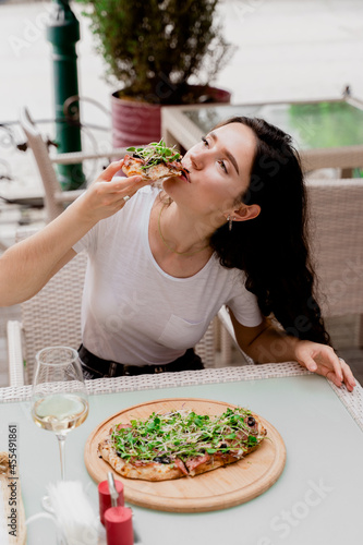 Girl with pinsa romana in cafe on summer terrace. Young woman eating pinsa and drinking wine photo