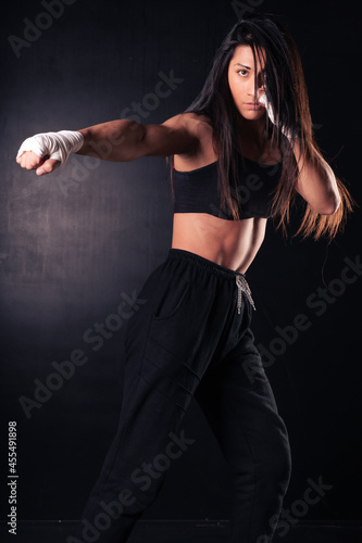 Young latin woman practicing boxing and kickboxing. She scores a direct punch with her fist. Sport, fitness, fitness, training concept.
