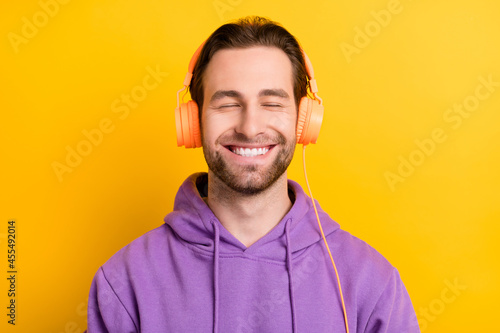 Photo of young man happy positive smile enjoy listen music headphones isolated over yellow color background