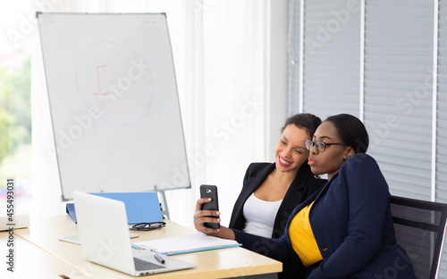 Beautiful african american and hispanic businesswoman working on laptop computer together at modern home office.