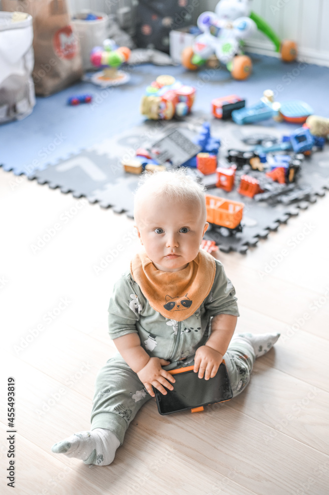 adorable cute baby boy playing with parents cell phone on the floor. happy childhood. adorable cute baby boy playing with parents cell phone on the floor. happy childhood.