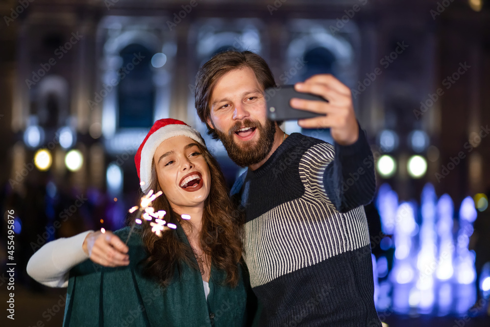Cute cheerful couple with sparklers rejoices on New Year's Eve c