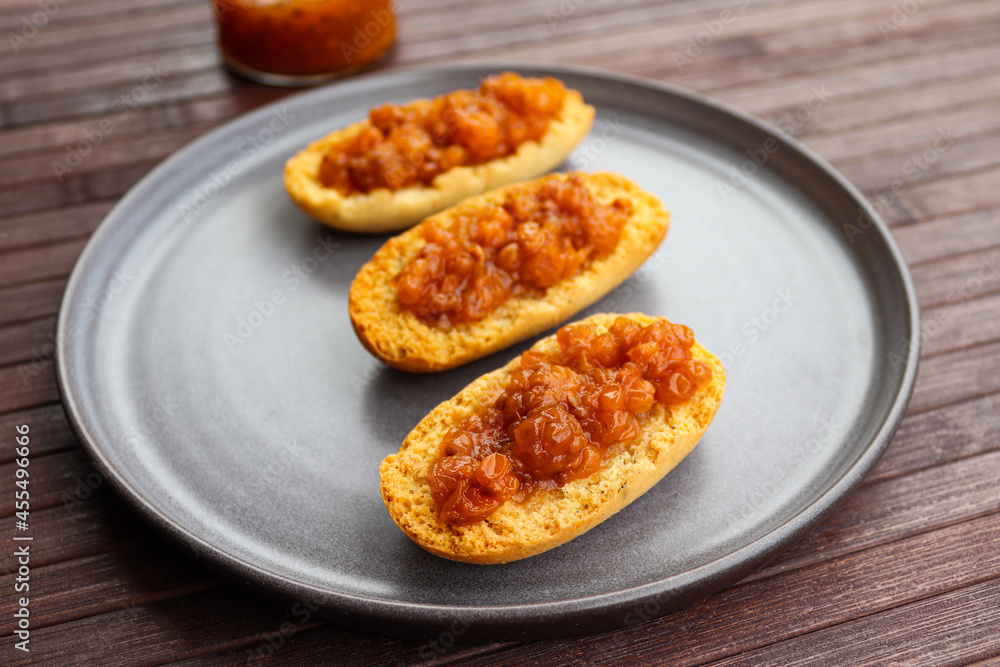 Cardamom rusks with cloludberry jam on gray plate