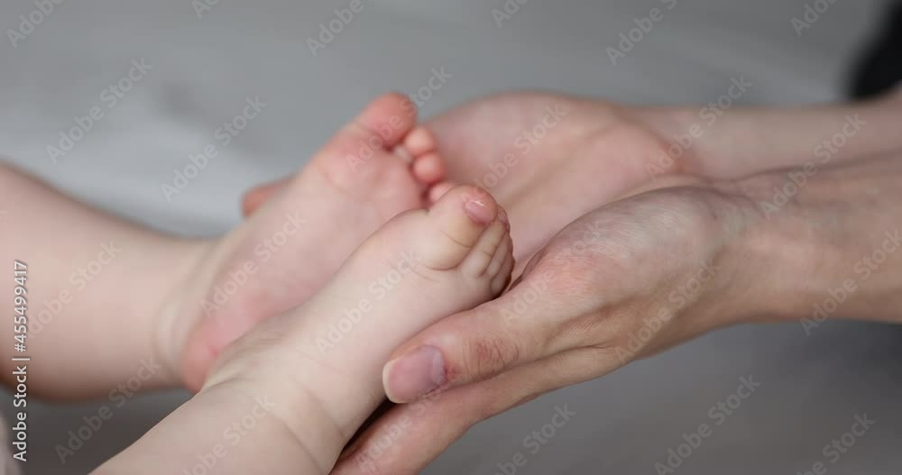 Mothers care and unconditional love concept. Close up view loving mom palms holds feet, tiny toes of her newborn baby. Unrecognizable woman touch legs of little kid, enjoy bonding with infant at home Mothers care and unconditional love concept. Close up view loving mom palms holds feet, tiny toes of her newborn baby. Unrecognizable woman touch legs of little kid, enjoy bonding with infant at home