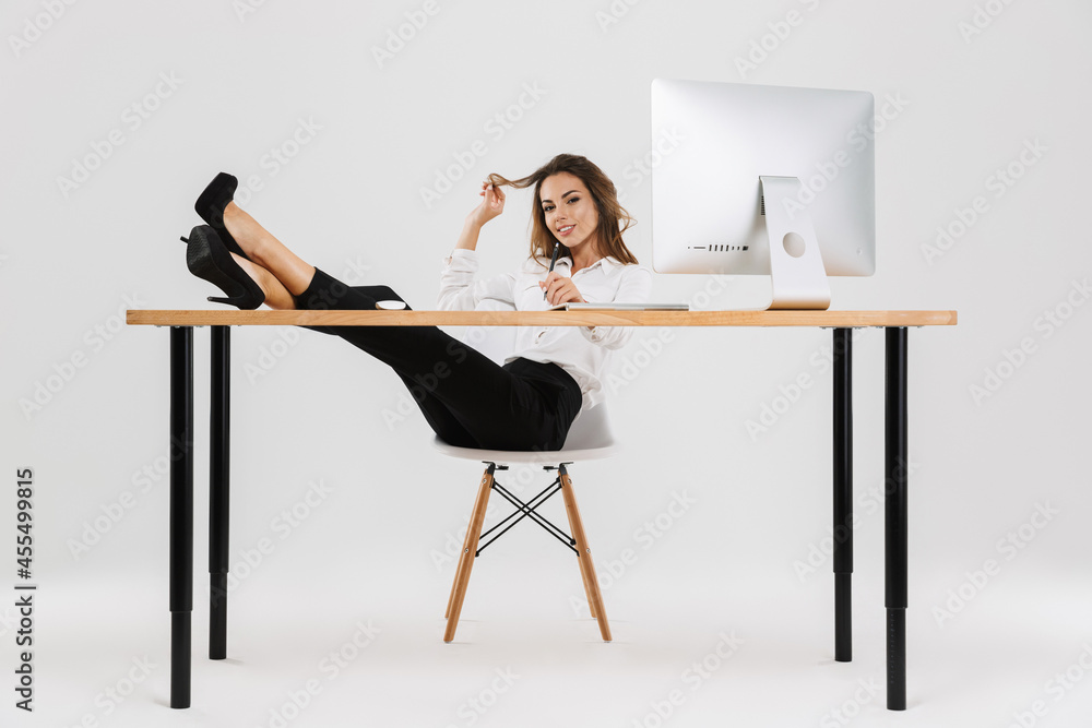 Ginger woman smiling while sitting and holding her legs on desk Ginger woman smiling while sitting and holding her legs on desk