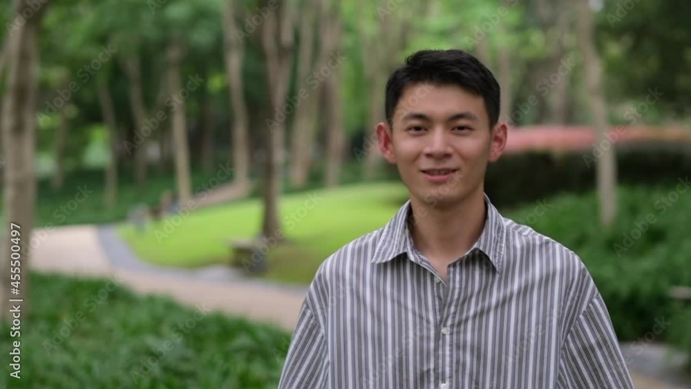 portrait of cute Asian young man smile at camera in natural park. Super slow motion portrait of cute Asian young man smile at camera in natural park. Super slow motion