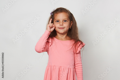 Girl pointing finger up against white background