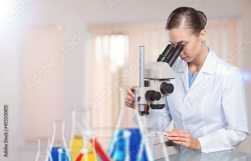 Young female scientist looking through a microscope.