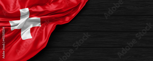 Close Up of Switzerland flag on the black wooden background 3D render