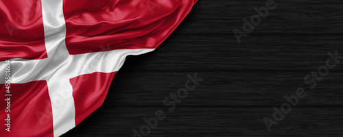 Close Up of Denmark flag on the black wooden background 3D render