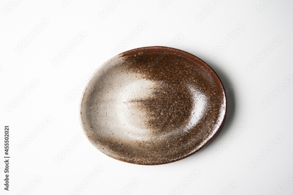 Top view of deep brown shading ceramic and oval plate on white backdrop Top view of deep brown shading ceramic and oval plate on white backdrop