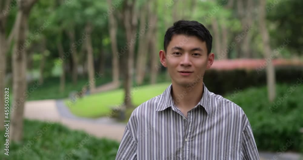 portrait of cute Asian young man smile at camera in natural park. Slow motion portrait of cute Asian young man smile at camera in natural park. Slow motion