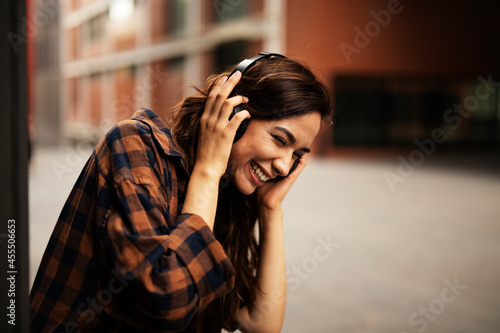 Young smiling woman with headphones outdoors. Beautiful happy girl listening the music.