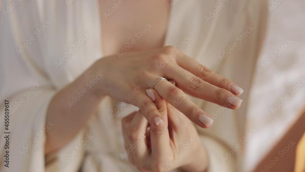 Beautiful lovely bride in night gown and veil put engagement ring on. Hands close up. Pretty, well-groomed gorgeous woman stay near window. Wedding morning preparation, positive mood. Slow motion Beautiful lovely bride in night gown and veil put engagement ring on. Hands close up. Pretty, well-groomed gorgeous woman stay near window. Wedding morning preparation, positive mood. Slow motion