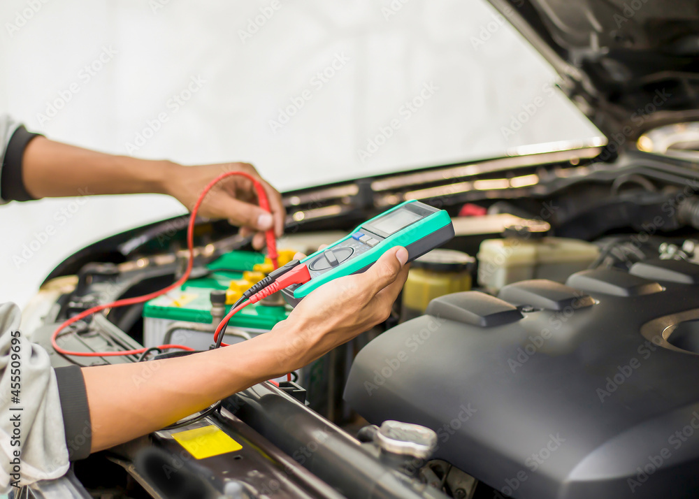 A technician is checking the car battery for availability.;	