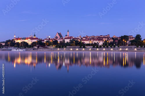 Illuminated Warsaw Old Town landscape with the Royal Castle, Cathedral and medieval buildings, night view with reflections in calm Vistula river, Poland.