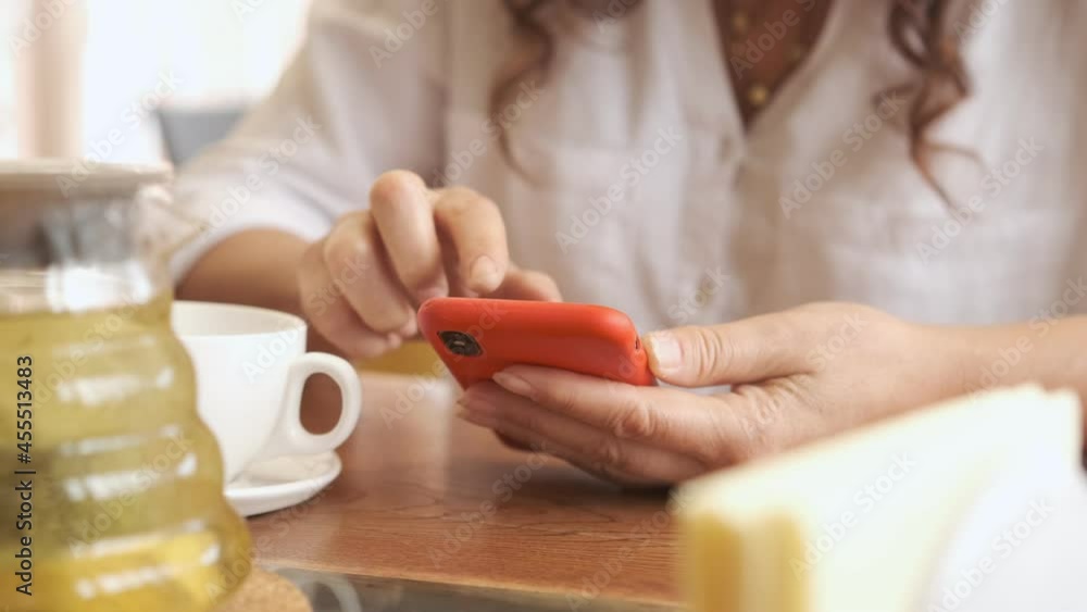 Closeup business woman typing message on mobile phone at restaurant. Close up young woman hands using smartphone . Closeup business woman typing message on mobile phone at restaurant. Close up young woman hands using smartphone .