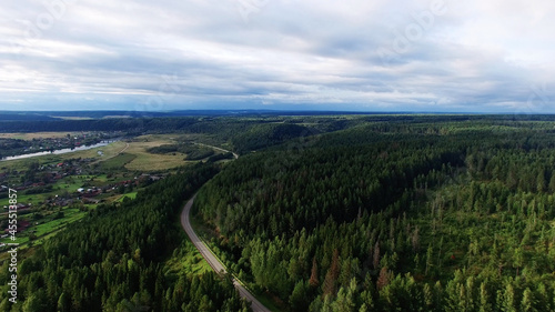 Aerial view of unlimited space of forest plain and cars which are riding on highway.