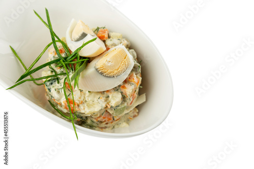 Russian salad Olivier in a white plate. A traditional winter snack for the holiday. Close-up. Isolated on white background. Space for text.