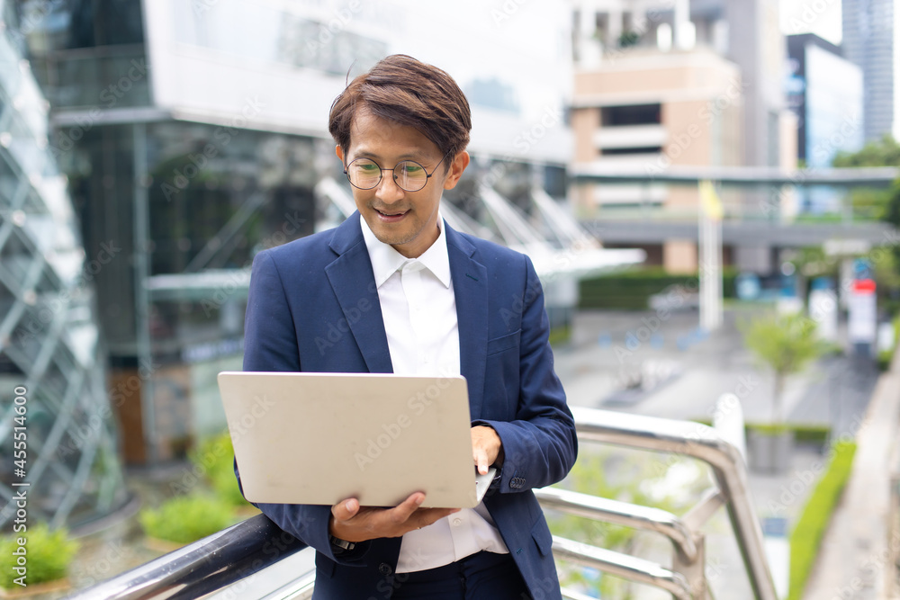 Handsome asian businessman working outdoors with computer