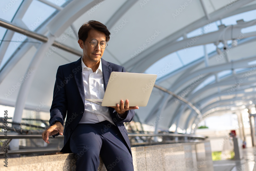Handsome asian businessman working outdoors with computer Handsome asian businessman working outdoors with computer