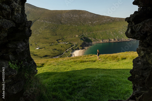 Photo of female traveler in Keem bay Achill Island Ireland through a window of an old building photo