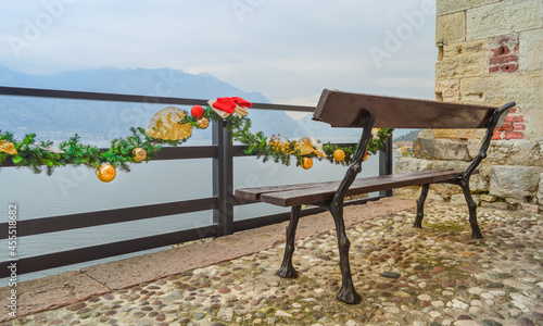 Bench in the Scaliger castle on the observation deck overlooking the mountains and Lake Garda. Christmas decorations and ornament on the railing of the fence.