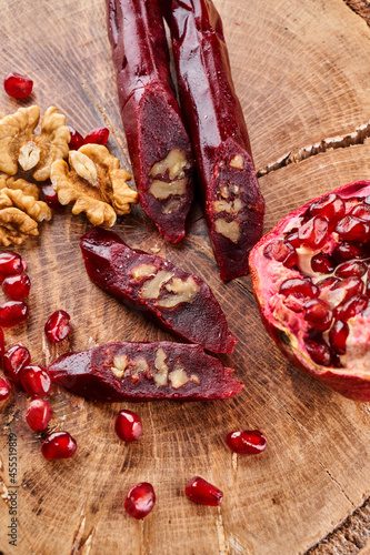 slicing Churchkhela, pomegranate and nuts on a wooden background, top view, serving