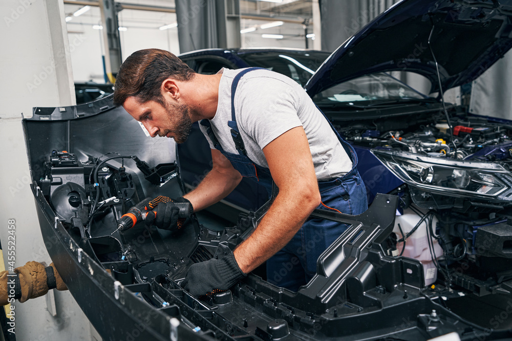 Automobile mechanic using drill on car part Automobile mechanic using drill on car part