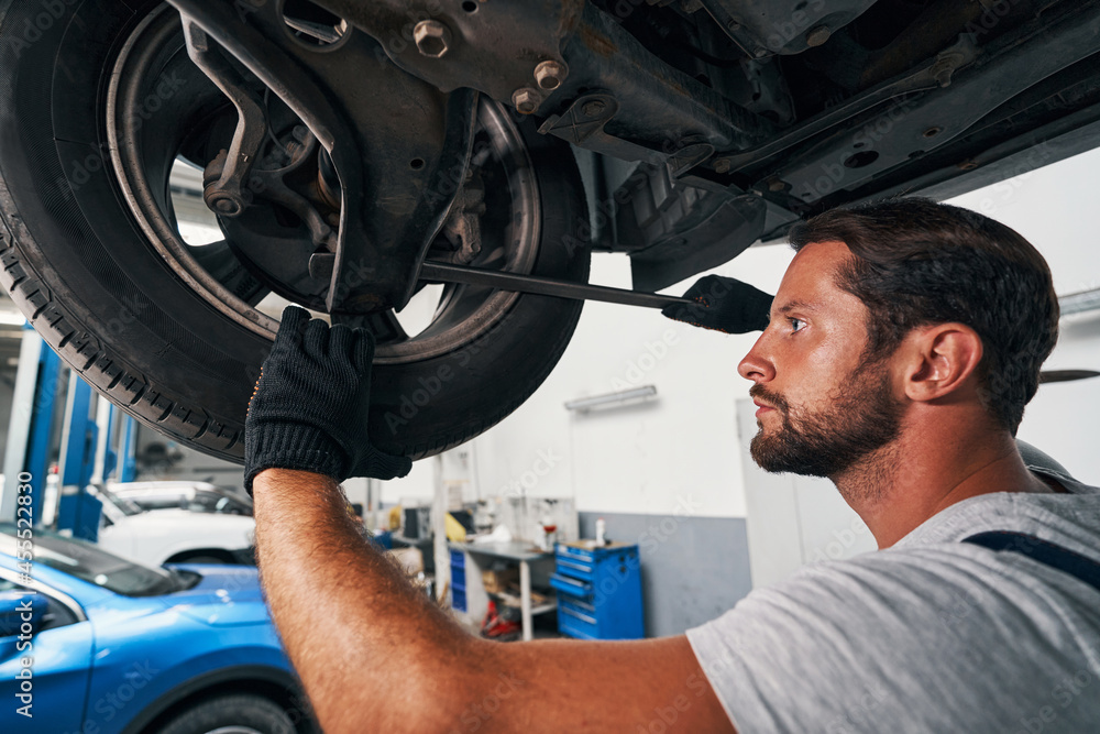 Male specialist checking car suspension with crowbar Male specialist checking car suspension with crowbar