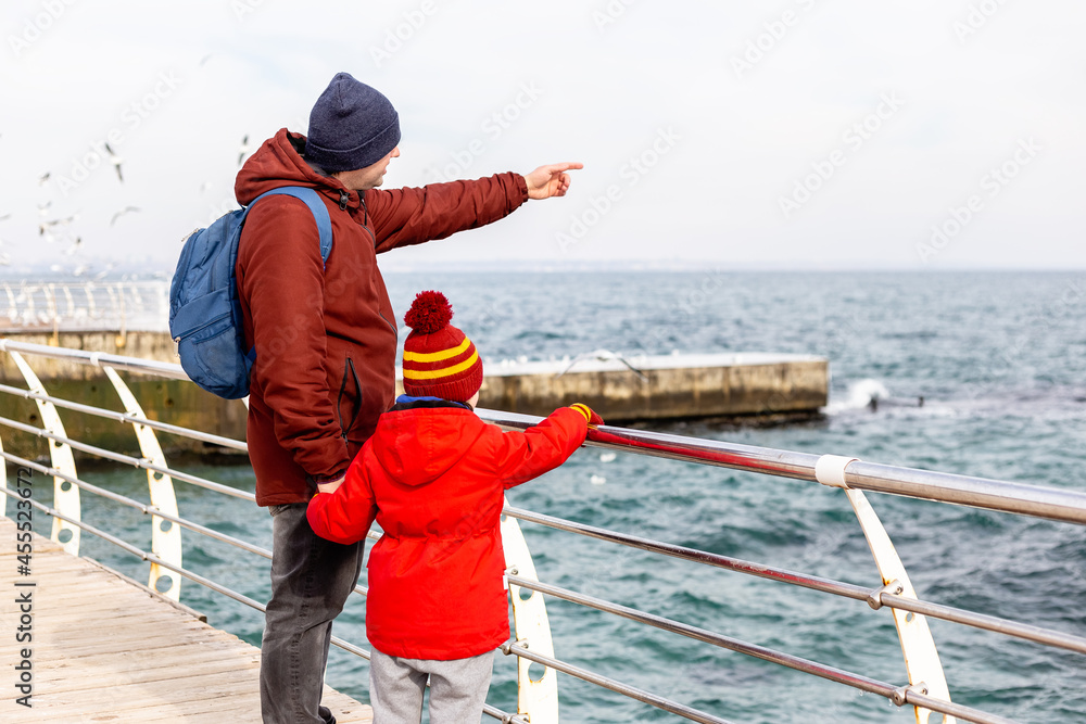 Father and son standing at the sea in winter