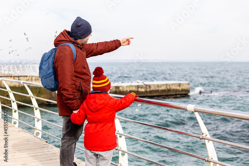 Father and son standing at the sea in winter