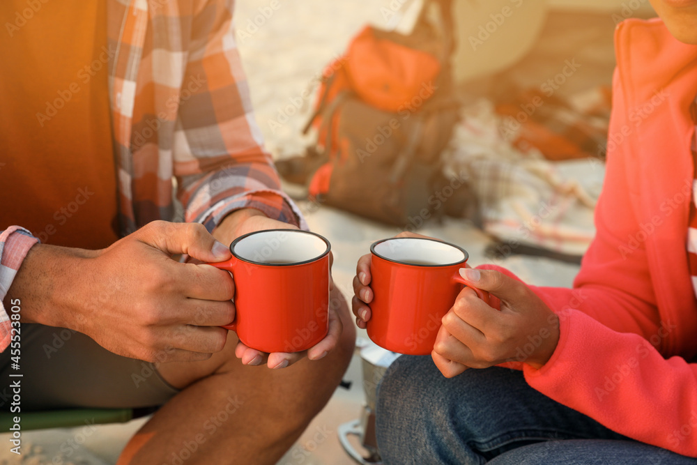 Couple with cups of hot drinks outdoors, closeup. Beach camping Couple with cups of hot drinks outdoors, closeup. Beach camping