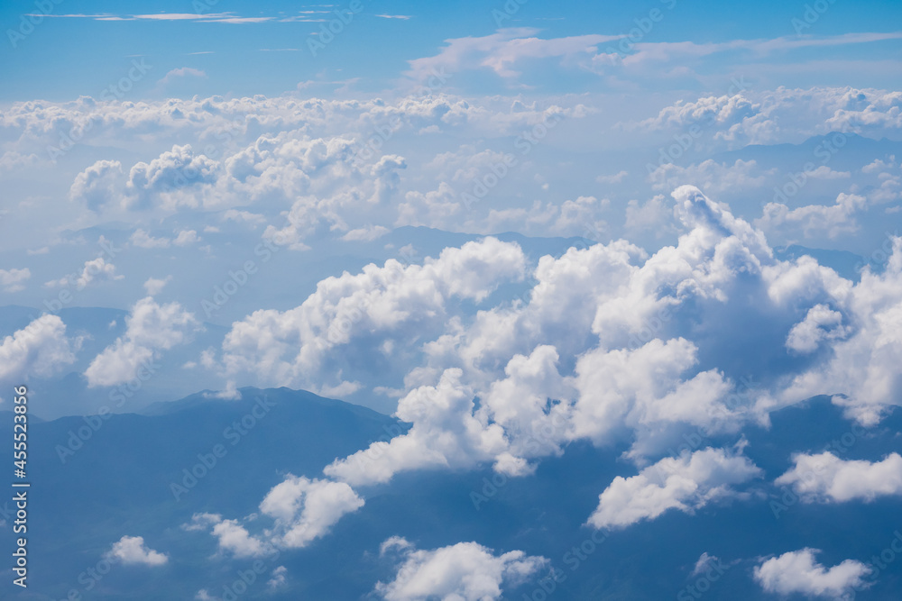 Aerial view scene of the mountain which hiding under white fluffy clouds and blue bright sky background. Aerial view scene of the mountain which hiding under white fluffy clouds and blue bright sky background.