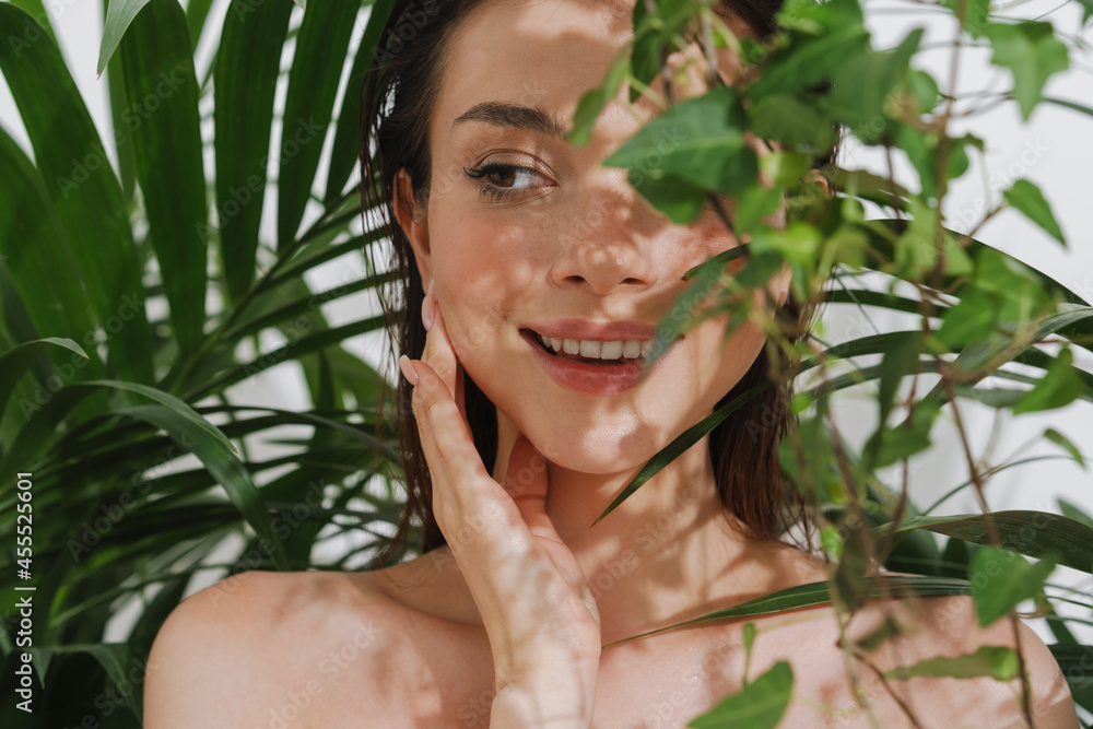 Young half-naked woman posing with plants on camera Young half-naked woman posing with plants on camera
