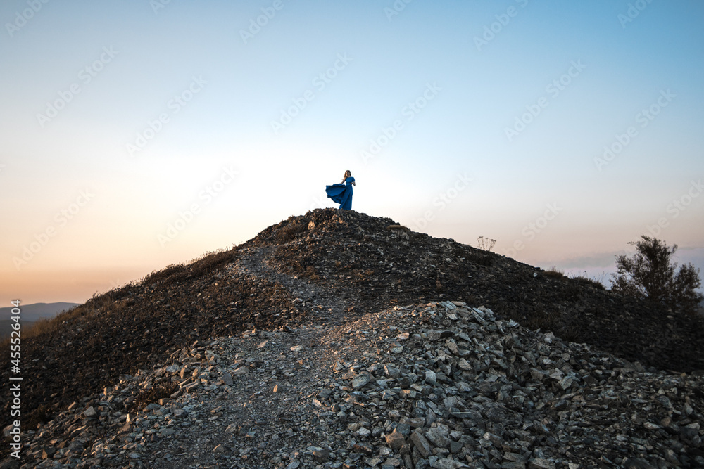 Girl on top of a stone mountain in a blue dress