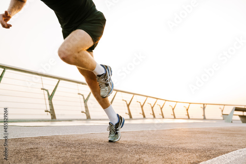 Young sportsman running while working out on city bridge