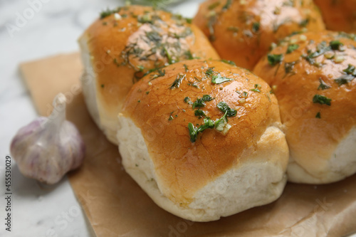 Traditional pampushka buns with garlic and herbs on white table, closeup photo