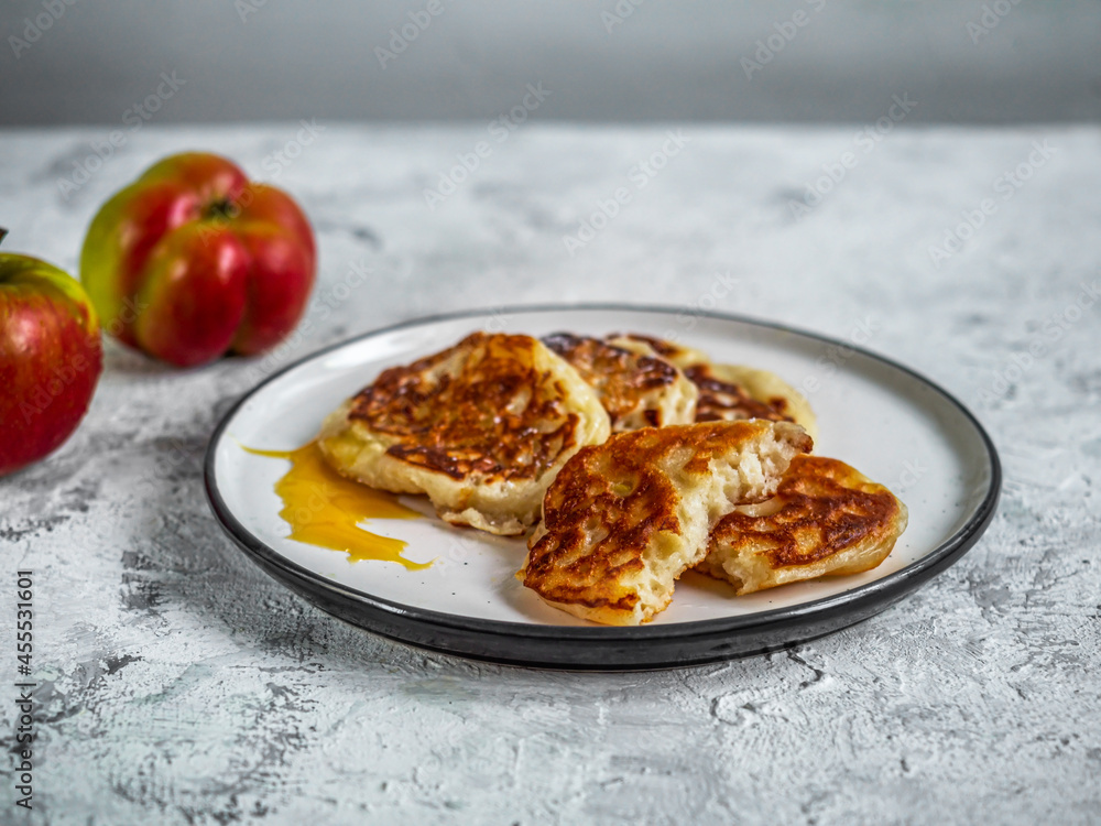 Apple pancakes and dessert fork on a light plate and red and yellow apples Apple pancakes and dessert fork on a light plate and red and yellow apples