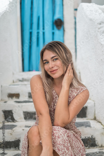 Close-up portrait of pretty caucasian blond girl with attractive blue eyes in casual dress. Sitting outdoors and smiling. © Aleksandr