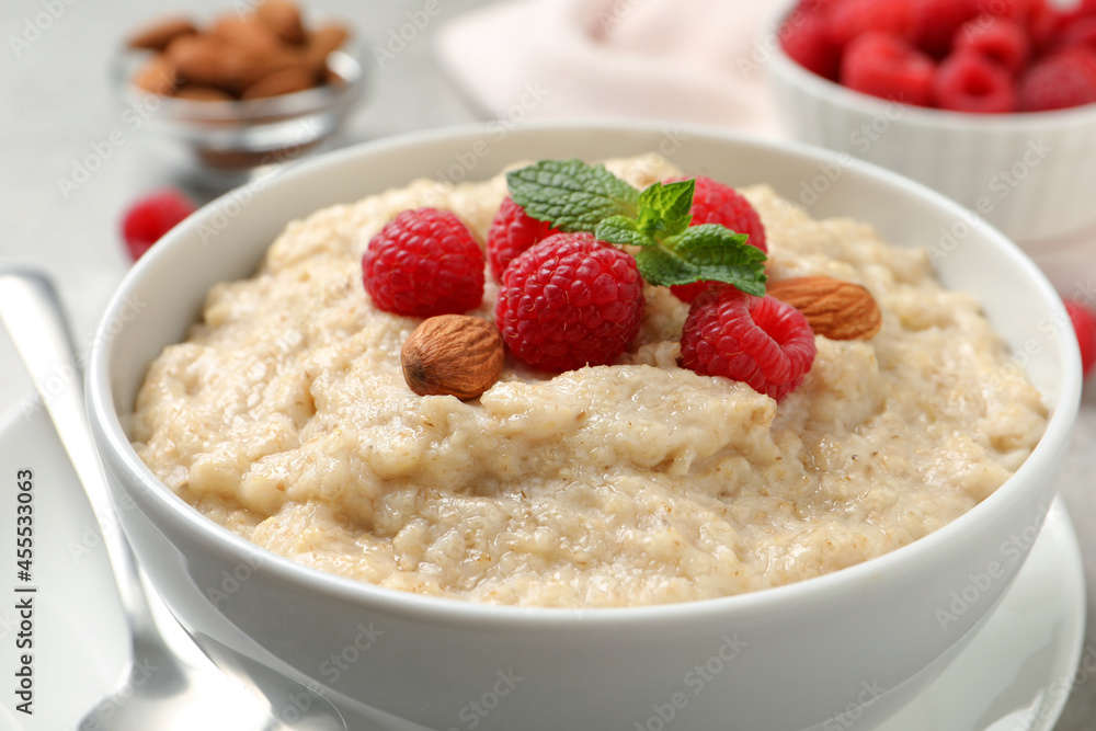 Tasty oatmeal porridge with raspberries and almond nuts in bowl on table, closeup Tasty oatmeal porridge with raspberries and almond nuts in bowl on table, closeup