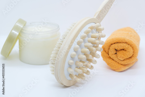 Double-sided massage brush for body brushing, towel and body scrub on white background. Pins of wood, natural bristle for removing of cellulite and stimulating lymphatic system. Materials for spa photo