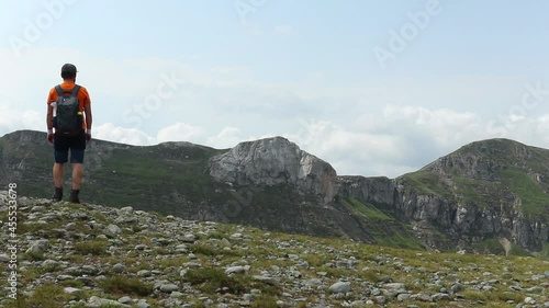 An HD footage of a man standing on the edge of a hill and looking at the landscape photo