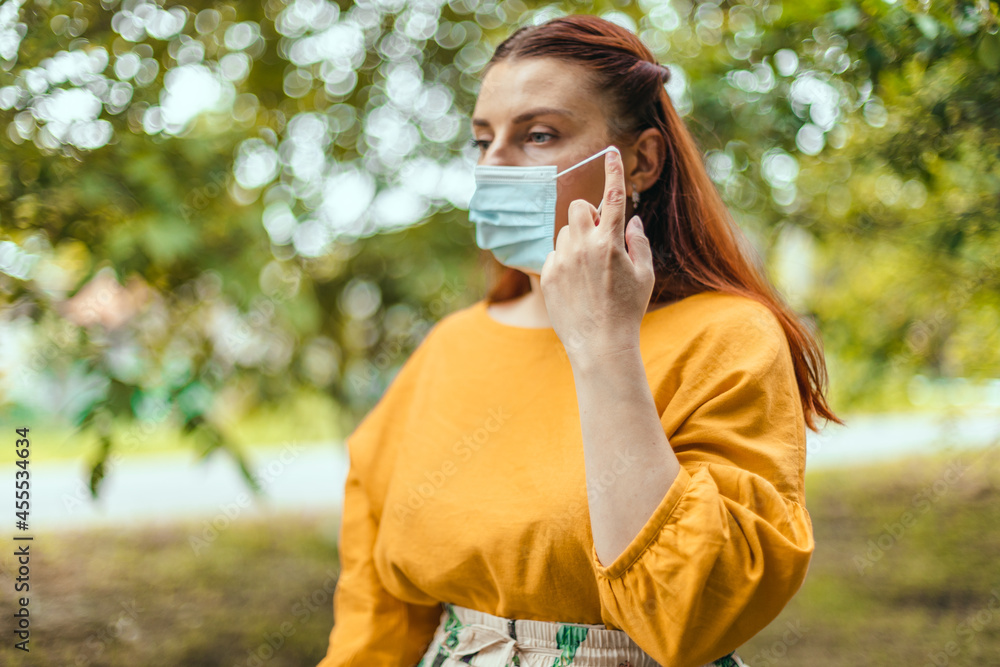 Caucasian woman taking off protective medical mask in city park. We won. No more quarantine. Caucasian woman taking off protective medical mask in city park. We won. No more quarantine.