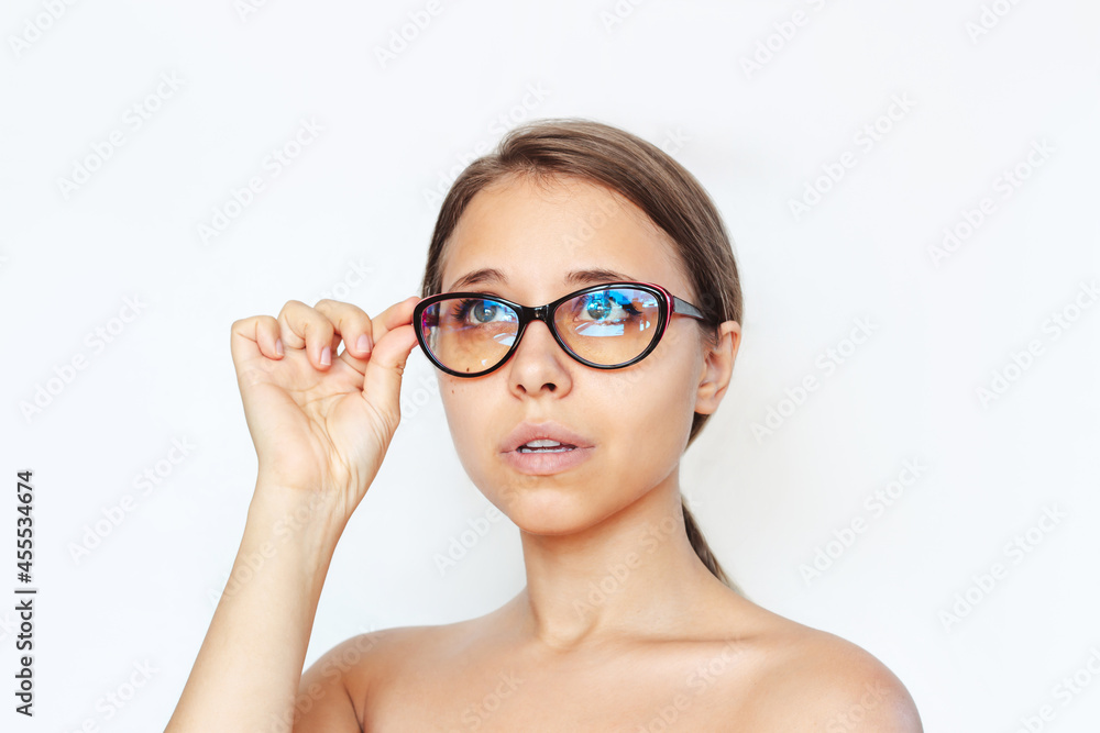 Close-up of a young caucasian woman with red and black female glasses for working at a computer with a blue filter lenses isolated on a white background. Anti blue light and rays. Eye protection Close-up of a young caucasian woman with red and black female glasses for working at a computer with a blue filter lenses isolated on a white background. Anti blue light and rays. Eye protection