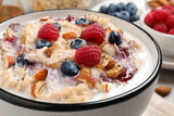 Tasty oatmeal porridge with toppings on table, closeup