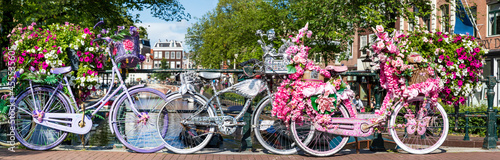 Amsterdam, Fahrräder auf einer Brücke mit Blumen bei den Grachten in Holland, ein Panorama. photo